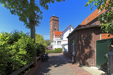 Borkum: Alte Insulanerhäuser mit Blick auf dem alten Leuchtturm..
